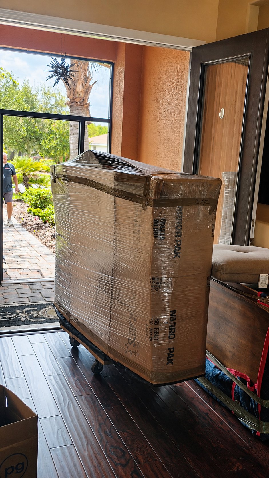 Large fragile item secured in a mirror carton with stretch wrap on a moving dolly